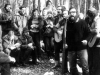 First Jewish Song Festival. Sitting on the log are two members of the jury: Zhenya Liberman (wearing a hat) and to his left, Ze'ev Prestin. Standing from right to left: Misha Rosenstein - singer with guitar; Arye Volvovsky - at the microphone, a leader of the festival; David Tokar - singer with a guitar; Misha Nudler - a leader of the Festival; Clara Lantzman – singer, with flowers; Lev Gorodetsky - Hebrew teacher (with glasses, jacket and a patterned sweater). Moscow, the Ovrazhki forest, Sukkot, 1977. co RS 